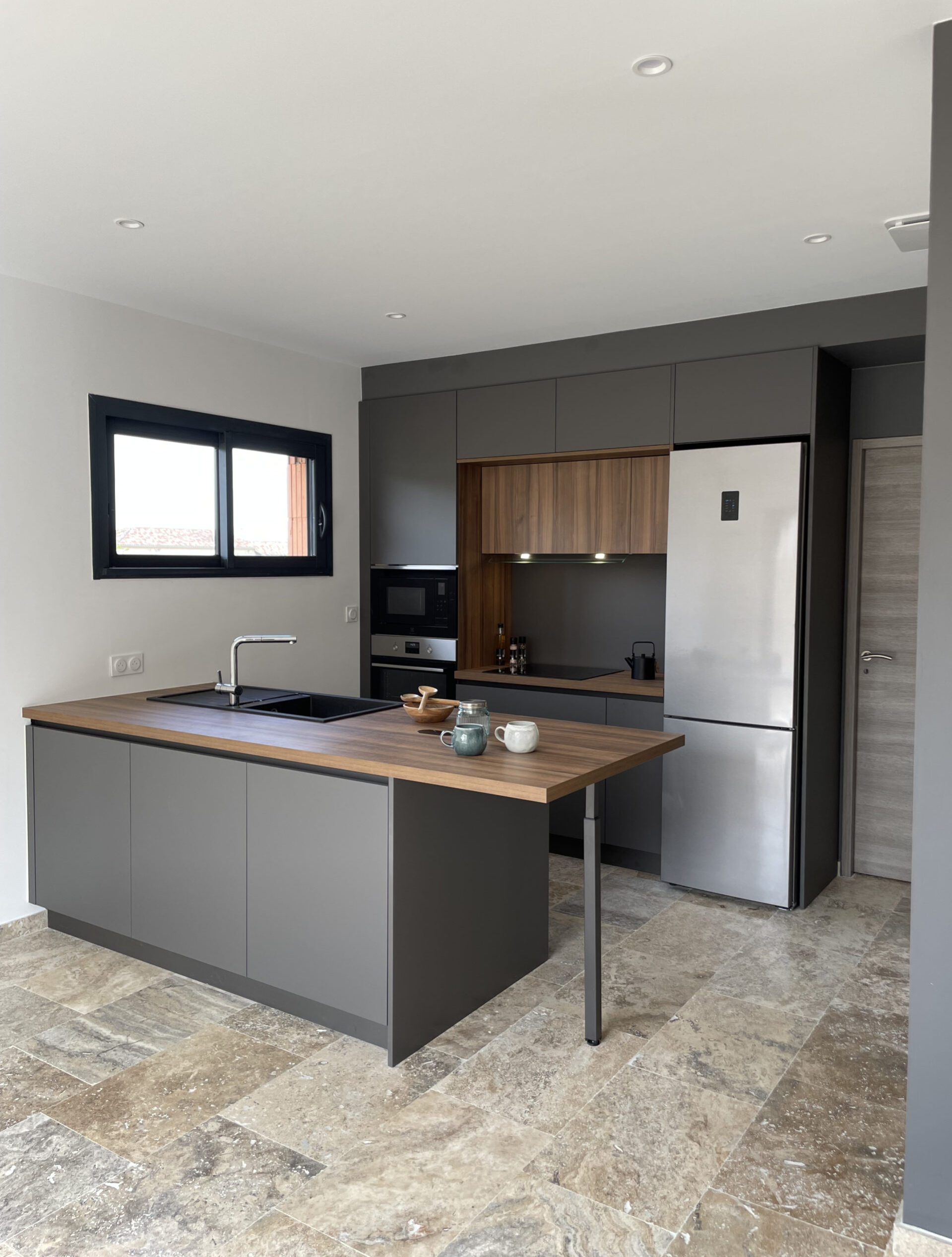 Cuisine sur-mesure avec un contraste élégant entre le bois foncé et le gris anthracite, éléments modernes et fonctionnels.