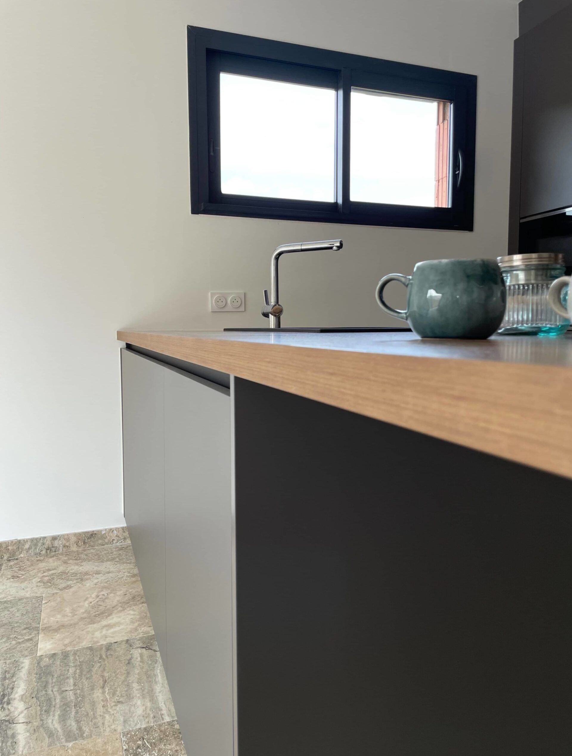 Plan de travail dégagé dans une cuisine sur-mesure avec niche de rangement pour appareils électroménagers